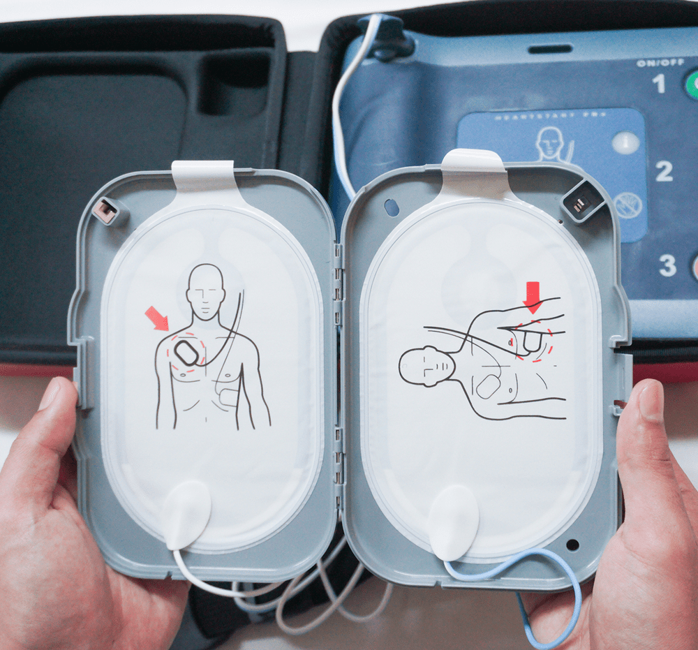 Hands holding AED pads and guide